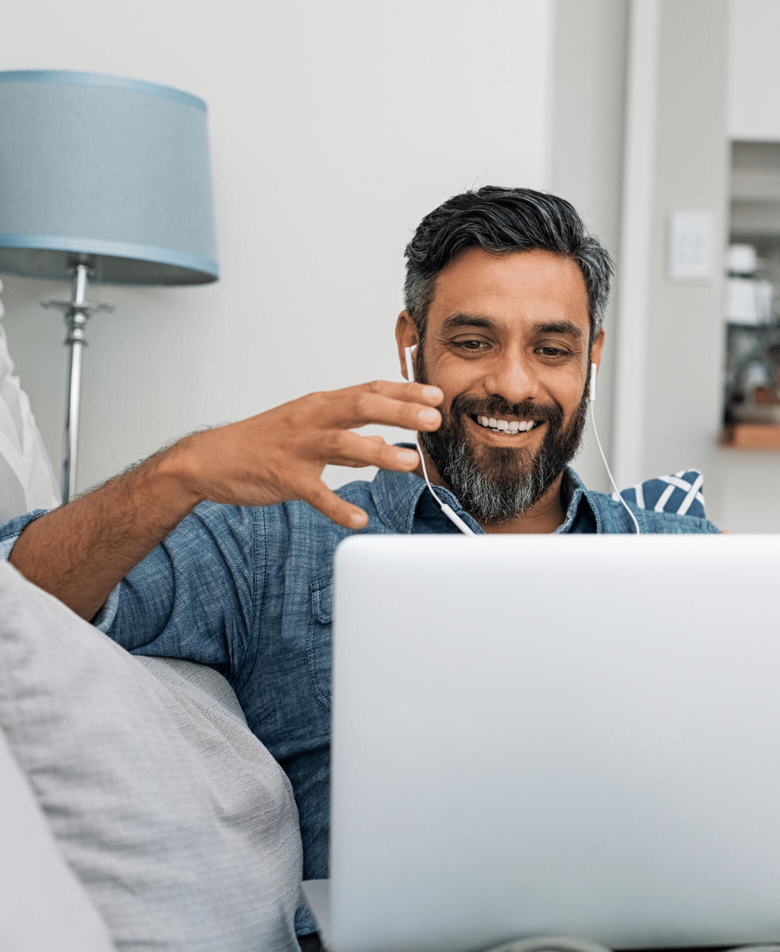 Man on laptop with headphones in, talking and smiling